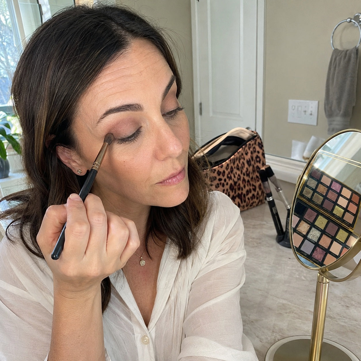Mature customer blending neutral eyeshadow in daylight