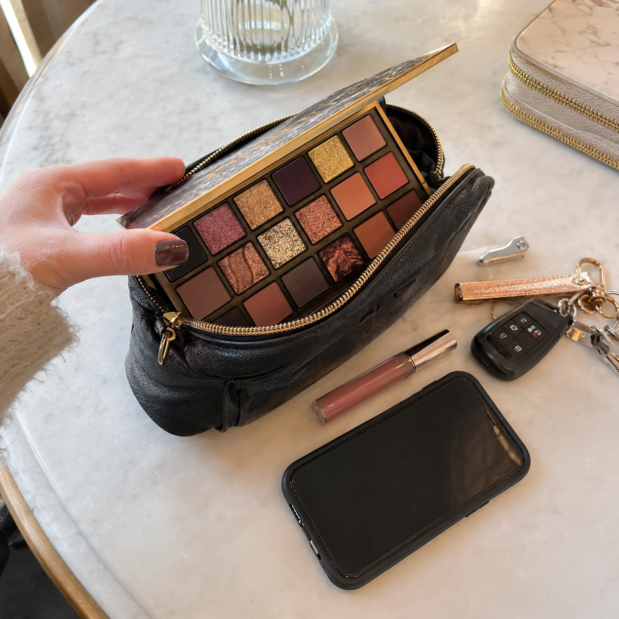 Eyeshadow palette packed inside a makeup bag with phone and keys