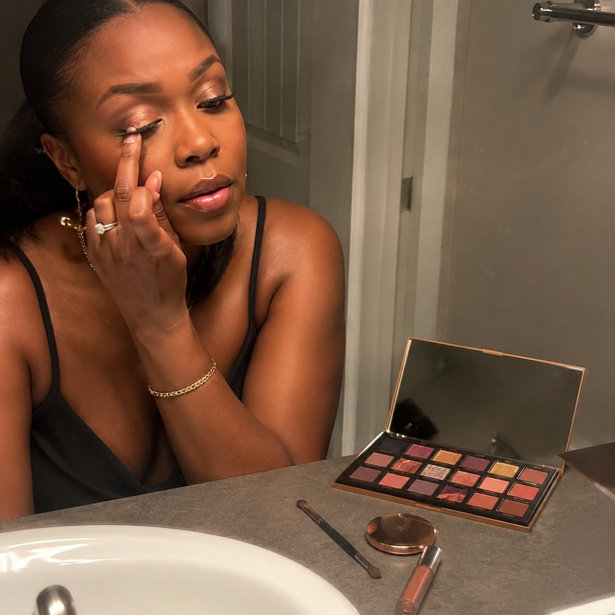 Customer touching up metallic eyeshadow in a bathroom before going out